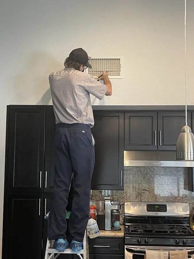 Technician inspecting an air vent during HVAC service in Westwood